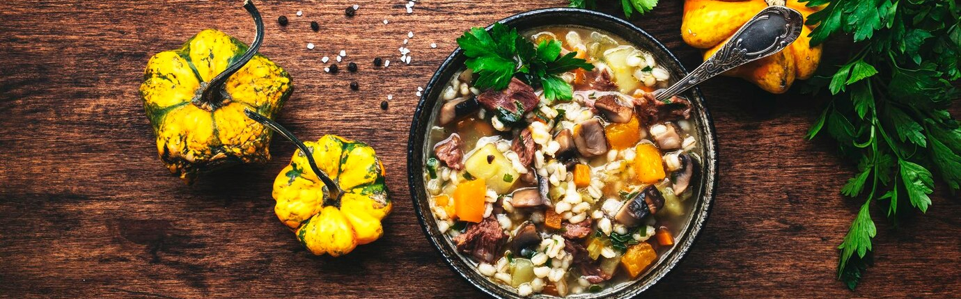 herbstessen-erwaermungssuppe-mit-kuerbispilzen-gemuese-rindfleisch-und-gerste-rustikaler-holztisch-hintergrund-draufsicht-banner_630207-7832 Kürbispilzgemüse mit Rindfleisch von Oben auf einem Holztisch. daneben kürbisse und frische kräuter